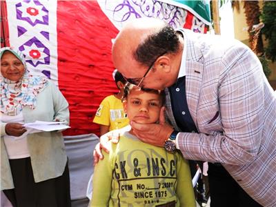  محافظ أسوان يقبل أحد لأطفال الأيتام 