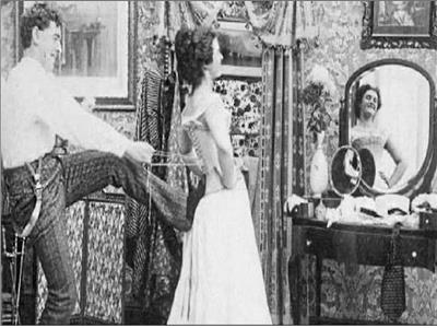 رجل يساعد المرأة على ارتداء الكورسيه عام 1910م وتتضح السخرية فى الصورة