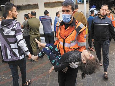 مسعف فلسطينى يحمل جثمان طفلة استشهدت فى غارة إسرائيلية 
