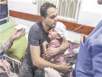 فلسطينى يحتضن طفله المصاب جراء القصف الاسرائيلى على غزة