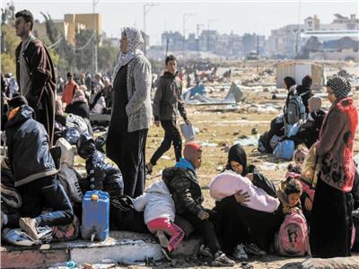 فلسطينيون ينتظرون على الرصيف أثناء فرارهم من خان يونس