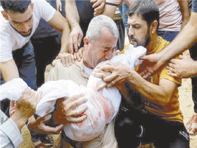فلسطينى يبكى بحرقة بينما يحتضن جثمان نجله