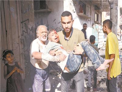 فلسطينى يحمل طفلا مصابا فى قصف إسرائيلى