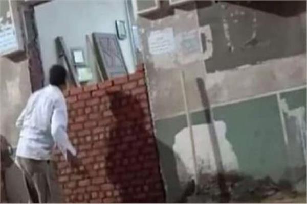 سيدة  تغلق باب مسجد بالفيوم بالطوب الأحمر