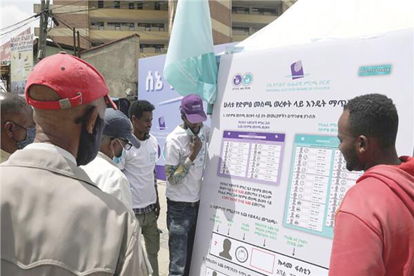 ناخبون امام لافتات تحمل اسماء المرشحين