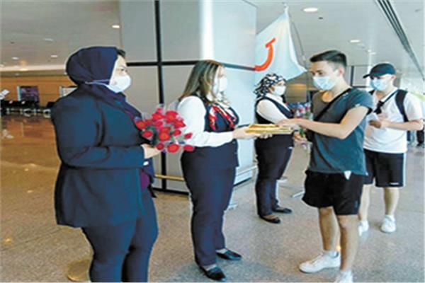 العاملون بالمطار يستقبلون السياح بالورود