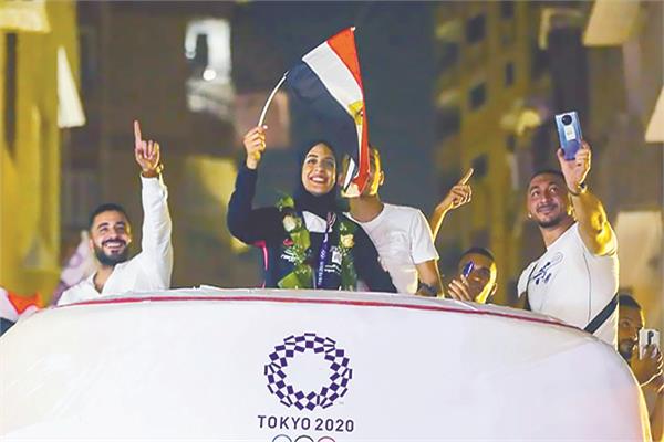 فريال البطلة الذهبية تلوح بعلم مصر فوق الباص المكشوفه بعد العودة الى مكان إقامتها المطرية