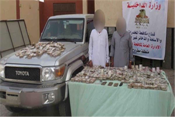 المتهمان وأمامهما المضبوطات