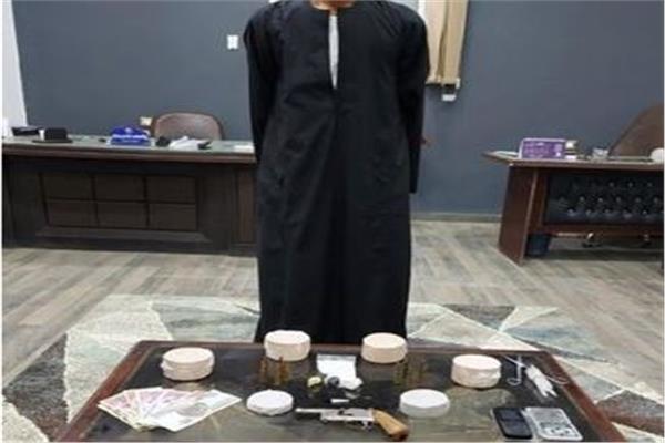 المتهم وأمامه المضبوطات