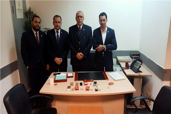 رجال الجمارك بمطار القاهرة وأمامهم المضبوطات 