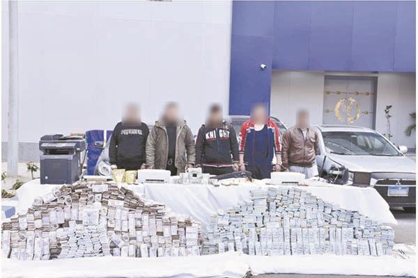 المتهمون وأمامهم كمية كبيرة من الأموال المزيفة