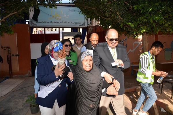 محافظ أسيوط يصطحب سيدة عجوز إلى داخل لجنة مدرسة الفاروق