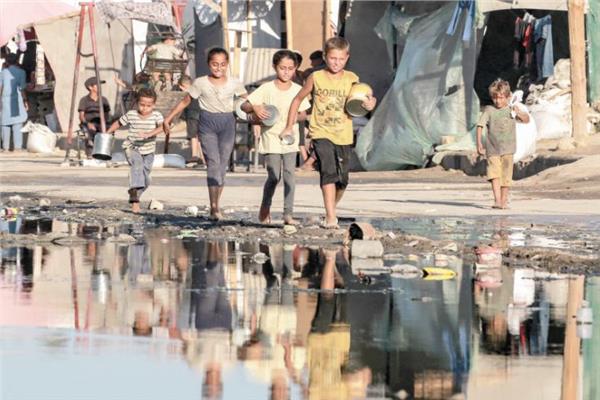 أطفال فلسطينيون يحملون أوعية فارغة