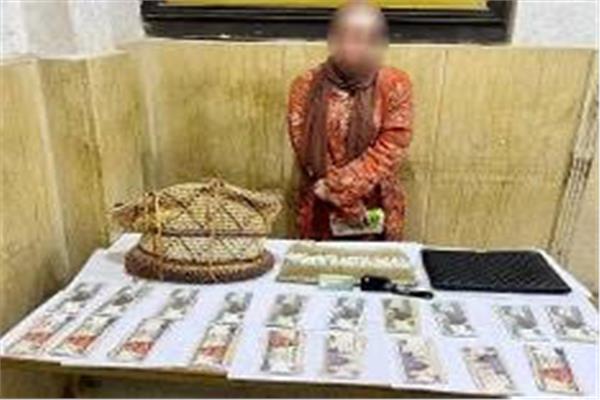 المتهمة وامامها المضبوطات