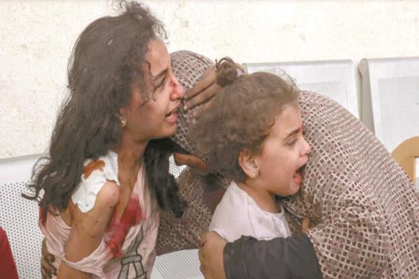 أم فلسطينية تحتضن بناتها المصابات من القصف الإسرائيلى