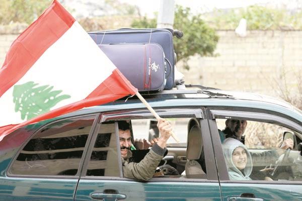 نازح يلوح بالعلم اللبنانى فى طريق عودته إلى بلدته 