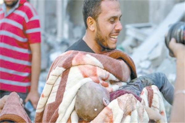 فلسطينى يحمل جثمان ابنه بعد انتشاله من تحت الأنقاض