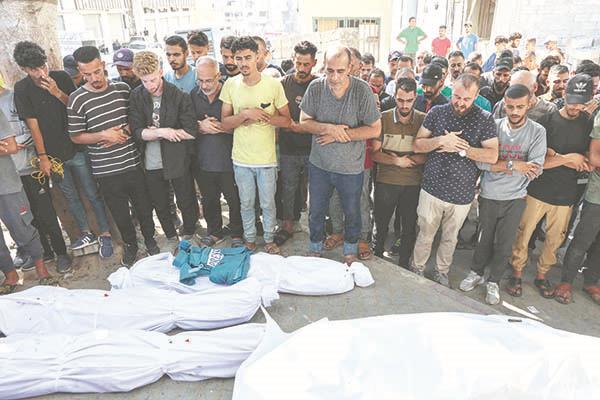 فلسطينيون يصلون على جثامين ضحايا القصف