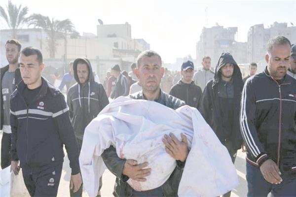 فلسطينى يحمل طفلًا ضحية العدوان الإسرائيلى