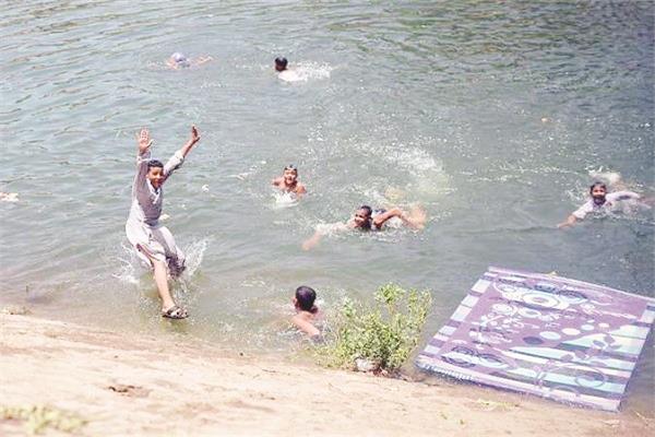 بعض أهالي قرية النمسا يسبحون في الترعة هروبََا من حر الصيف