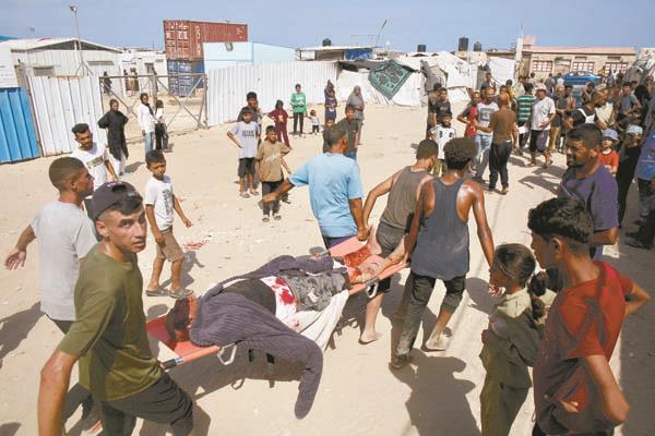 فلسطينيون يحملون أحد المصابين من منتظرى المساعدات فى غزة   
