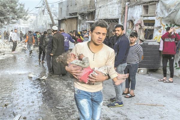 فلسطينى يحمل طفلة مصابة