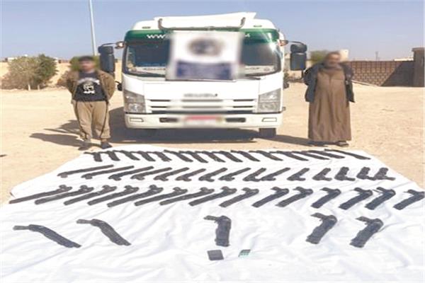 المتهمون وأمامهم الأسلحة المضبوطة