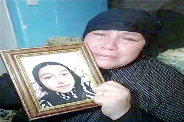 الأم تحتضن صوة ابنتها الضحية