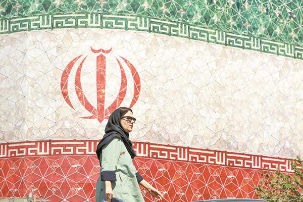 إيرانية تسير أمام جدارية كبيرة لعلم بلادها