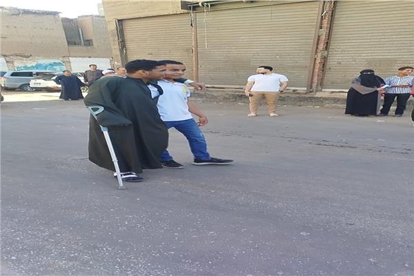طالب يساند زميله على عكاز أثناء دخوله لجنة الثانوية العامة بقنا