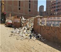 صور| أهالي العشرين بالهرم يعانون من تلال القمامة   